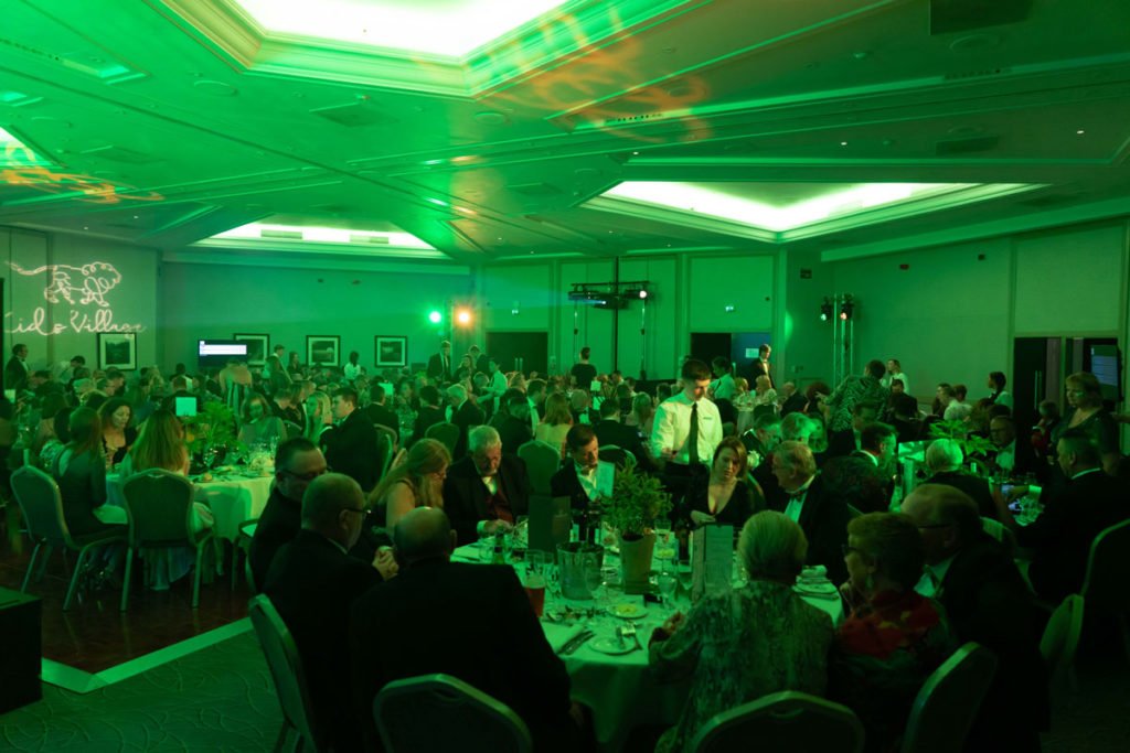 Kids Village Ball (green lit image of event room with guests)